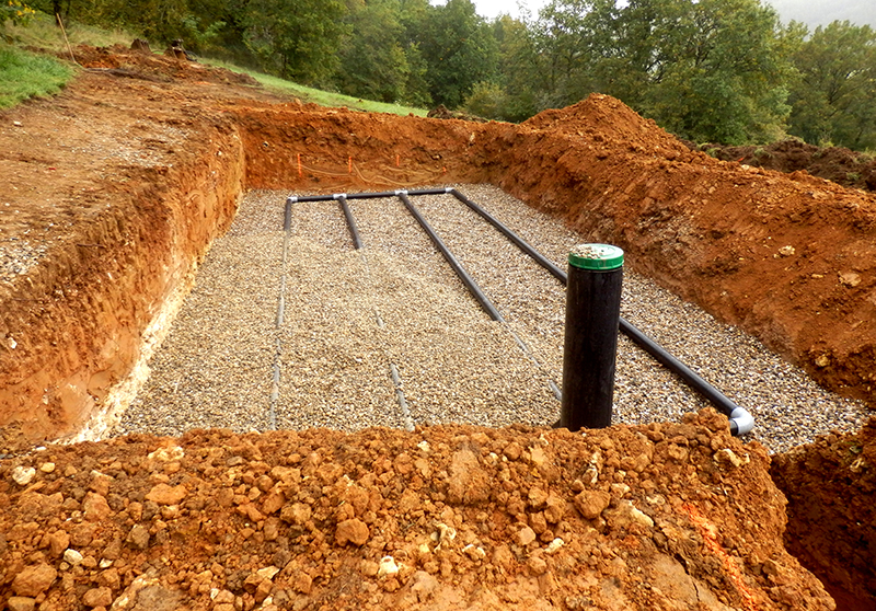 septic system drain field pipes installed in a freshly dug hole