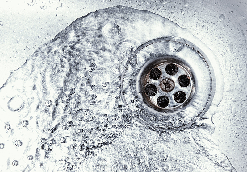 Water swirling down a drain of a stainless steel kitchen sink