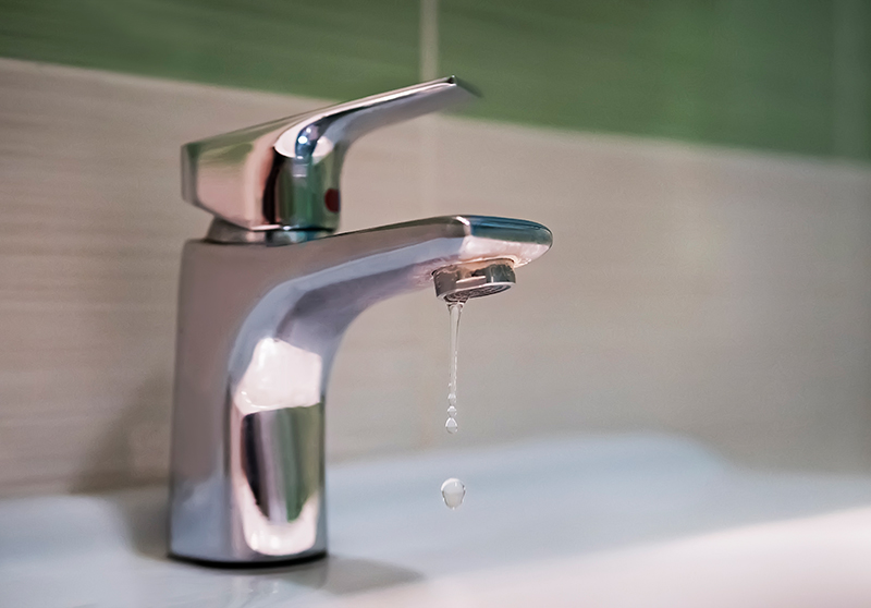 leaky silver, single-handled bathroom faucet dripping water