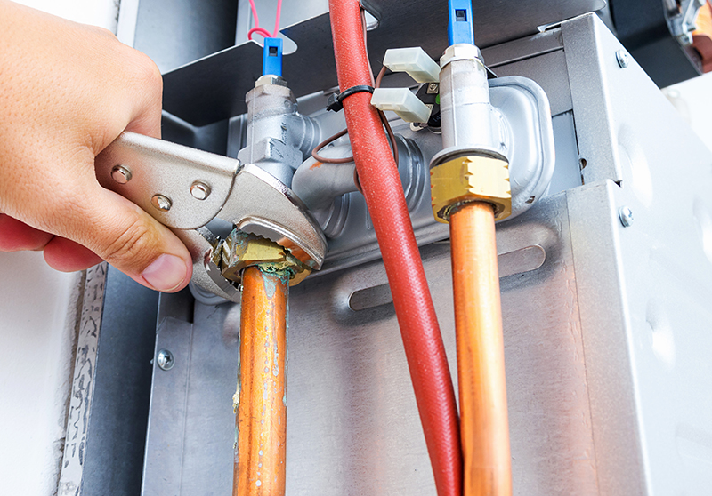 a man's hand holding pliers tightening the conector on a new plumbing line